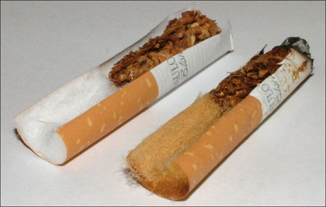 Neue Zigarette im Vergleich mit Zigarettenkippe: Rückstände aus dem Zigarettenrauch färben den gebrauchten Filter bräunlich.